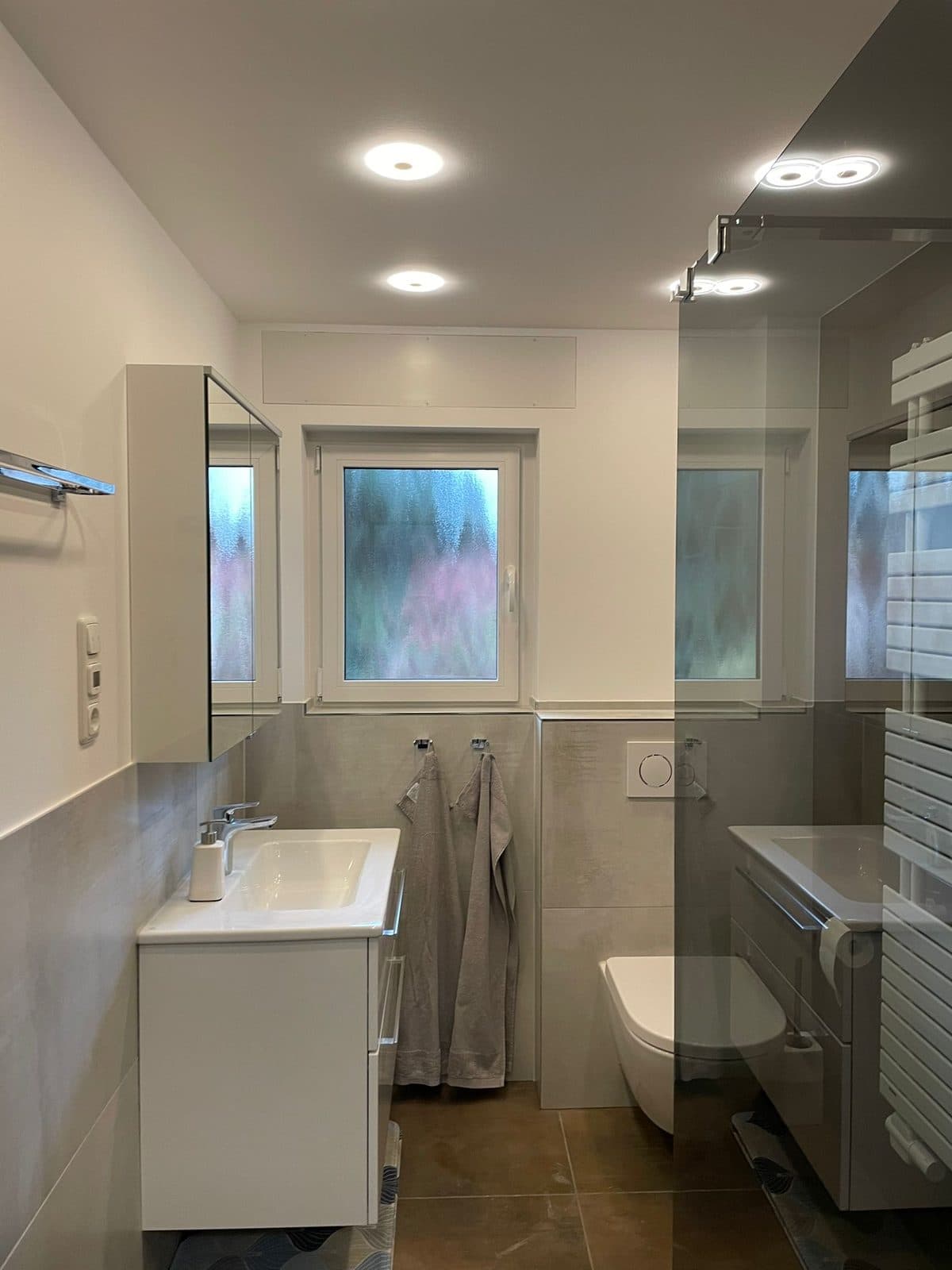 Modernes graues Badezimmer mit Waschtisch, Wand-WC und Walk-in-Dusche, Badsanierung von Kesmiris Darmstadt